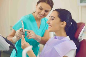 Satisfied client in dental chair looking at result of professional cleaning and whitening.